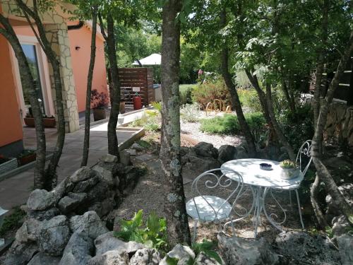 einen Tisch und einen Stuhl in einem Garten mit Felsen in der Unterkunft The Forest House Krk 2 in Kras