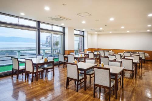 a dining room with tables and chairs and windows at Toya-onsen Hotel Hanabi in Lake Toya