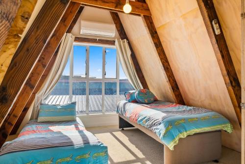 two beds in a room with a window at Alpha - Otaki Beach Holiday Home in Otaki Beach
