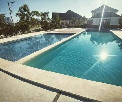 a large swimming pool with blue water in front of a house at Danarose residences rental in Bacoor