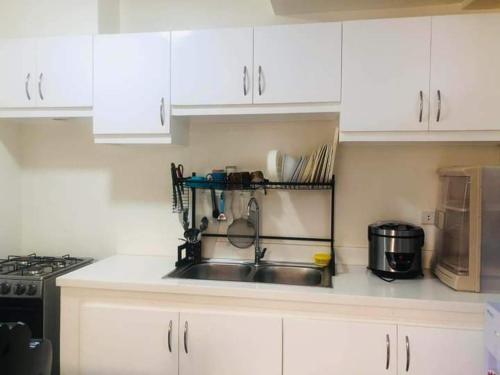 a kitchen with a sink and a stove and white cabinets at Danarose residences rental in Bacoor