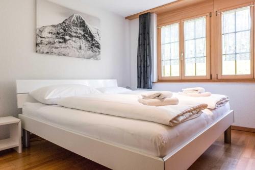 a bedroom with a large white bed with towels on it at Apartment Dolce Vita - GRIWA RENT AG in Grindelwald