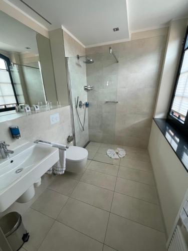 a bathroom with a shower and a toilet and a sink at Hotel Hafenresidenz Stralsund in Stralsund