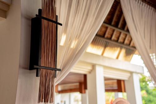 a cross hanging on the side of a room with curtains at The Lotus Residence by Amerta Experience in Tabanan