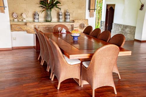 a dining room table with wicker chairs around it at The Lotus Residence by Amerta Experience in Tabanan
