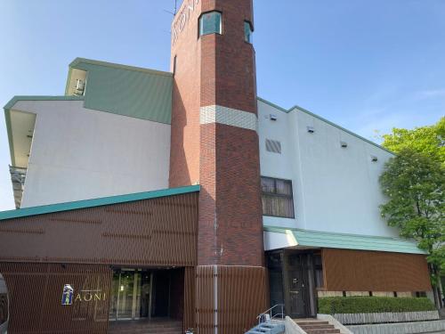 a building with a clock tower in front of it at 田沢湖水沢温泉郷セルリアンリゾートAoni in Senboku