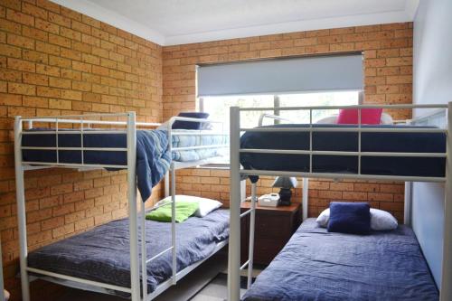a room with three bunk beds and a brick wall at Seacrest 5 South West Rocks in South West Rocks