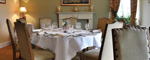a dining room table with a white table cloth and chairs at The Gower Golf Club B&B in Gowerton