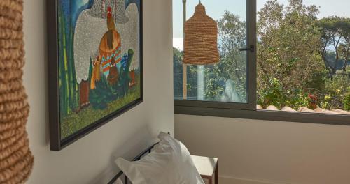 a room with a window and a painting and a pillow at L'Aixart Aiguablava Hotel in Begur