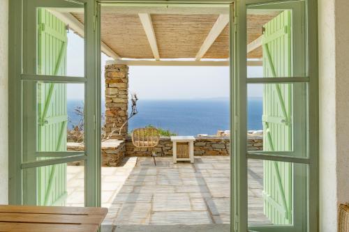 an open door to a patio with a view of the ocean at Casa Xyla-sunset view villa in Melissaki