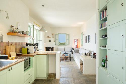 a kitchen with white cabinets and a living room at Casa Xyla-sunset view villa in Melissaki