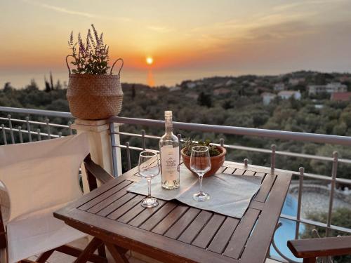 een houten tafel met twee glazen en een fles wijn bij Villa Elenia in Tsoukaladhes