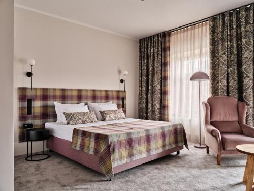 a hotel room with a bed and a chair at Hoppen House Apartamenty w centrum miasta in Radom