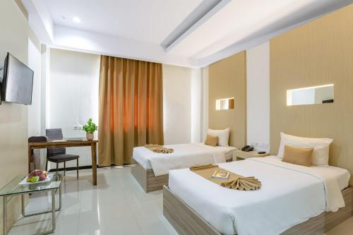 a hotel room with two beds and a desk at Sahid Azizah Syariah Hotel and Convention Kendari in Lepoleop