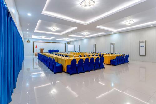 a conference room with blue and yellow tables and chairs at Sahid Azizah Syariah Hotel and Convention Kendari in Lepoleop
