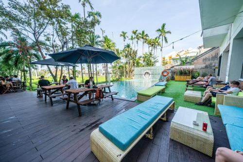 a patio with people sitting around tables and a pool at Mad Monkey Hoi An in Hoi An
