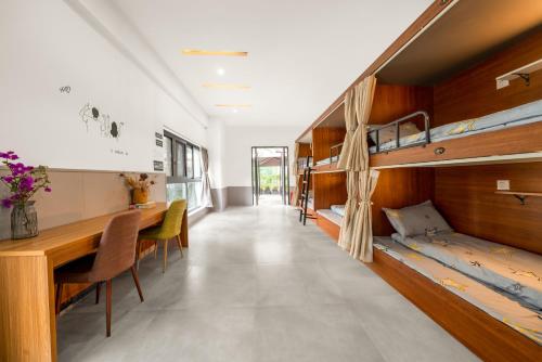 a room with bunk beds and a desk and a table at Riverside International Youth Hostel阅江老院青年旅舍 in Chongqing
