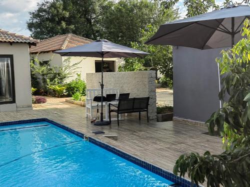 a patio with a table and umbrella next to a pool at Nandoni Crystal in Thohoyandou
