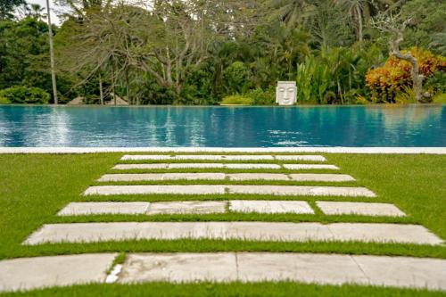 a stepping stone pathway in front of a pool of water at The Lotus Residence by Amerta Experience in Tabanan