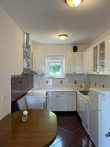 a kitchen with white cabinets and a wooden table at Apartments Cvjetković in Mlini