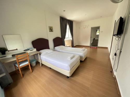 a hotel room with two beds and a desk at Dear Dino Villa Cameron Highlands in Cameron Highlands