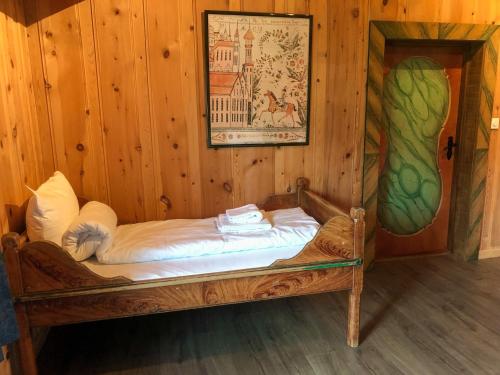 Cama pequeña en habitación de madera con una pintura en Vågåvatnet Feriesenter, en Vågåmo