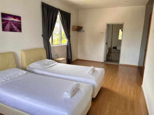 two beds in a hotel room with a window at Dear Dino Villa Cameron Highlands in Cameron Highlands