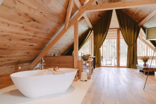 ポストイナにあるPIRA HOTELの木製の天井の部屋にある大きな浴槽付きのバスルーム