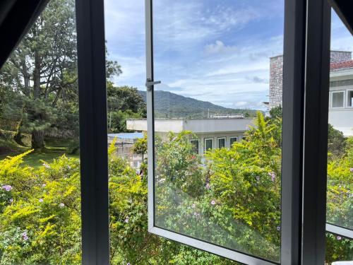 an open window with a view of a garden at Dear Dino Villa Cameron Highlands in Cameron Highlands