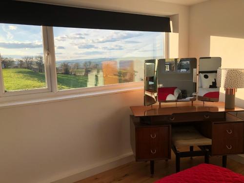 a bedroom with a desk and a large window at Black Mountain Views in Velindre