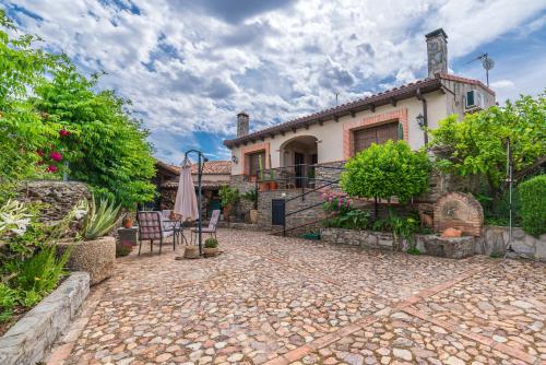 una casa con un patio y una sombrilla delante de ella en La Jara · Apartamentos Rurales en Serrejón