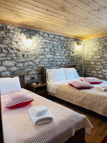 two beds in a room with a stone wall at Medieval Rooms in Gjirokastër