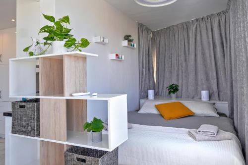 a small bedroom with a bed and a shelf with plants at AZURE VIEW Ponderosa 719 in Playa Fañabe
