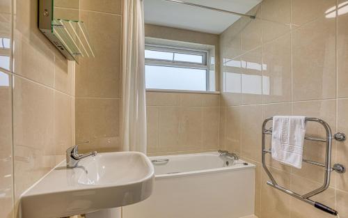 La salle de bains est pourvue d'un lavabo et d'une baignoire. dans l'établissement Ilex Lodge, à Saint-Pierre-Port