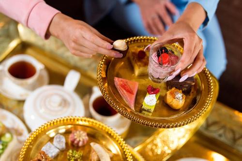 a person holding a plate of food on a table at Sharq Village & Spa, a Ritz-Carlton Hotel in Doha