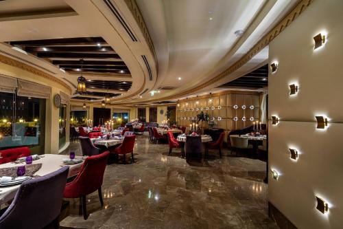 a dining room with tables and red chairs at Sharq Village & Spa, a Ritz-Carlton Hotel in Doha