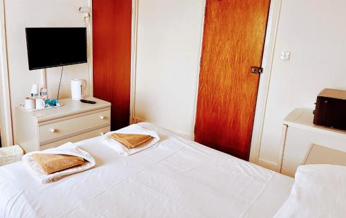 a bedroom with a white bed and a television at St George Hotel Great Yarmouth in Great Yarmouth