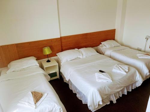 three beds in a room with white sheets at St George Hotel Great Yarmouth in Great Yarmouth