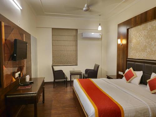 a hotel room with a bed and a desk and a tv at Hotel Prime Safari in Jaipur