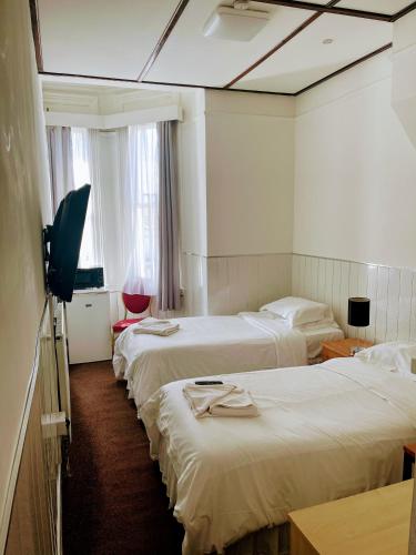 a hotel room with three beds and a television at St George Hotel Great Yarmouth in Great Yarmouth