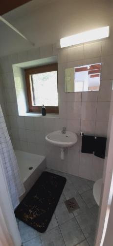 a white bathroom with a sink and a tub and a window at Prém Malom Vendégház in Bakonynána