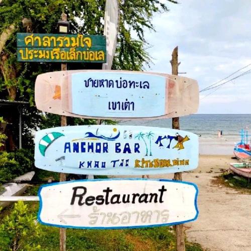 a group of signs on a pole next to the beach at Las Tortugas, Cozy condominium on Khao Tao beach, Hua Hin in Khao Tao