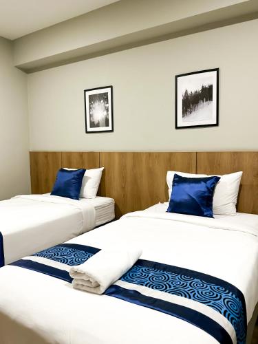 two beds in a hotel room with blue pillows at B Stay Hotel in Bangkok