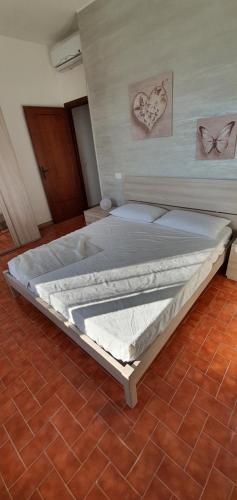 a large bed in a room with a brick floor at Lovely house tra pineta e mare in Torre di Montalto