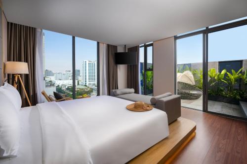 a bedroom with a large white bed and large windows at Estrella Boutique Hotel in Da Nang