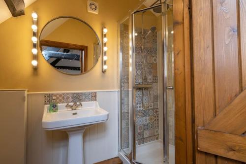 a bathroom with a sink and a mirror and a shower at Canons Court Lodge in Wotton-under-Edge