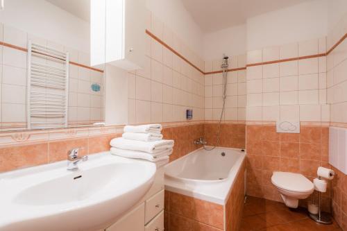 a bathroom with a sink and a tub and a toilet at EA ApartHotel Melantrich in Prague