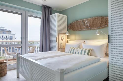 a bedroom with a large white bed and a balcony at Beach Apartments Büsum in Büsum