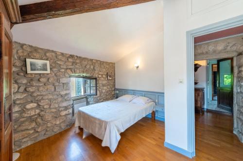ein Schlafzimmer mit einem Bett und einer Steinmauer in der Unterkunft La Médiévale - Charmante maison de caractère in Ruoms