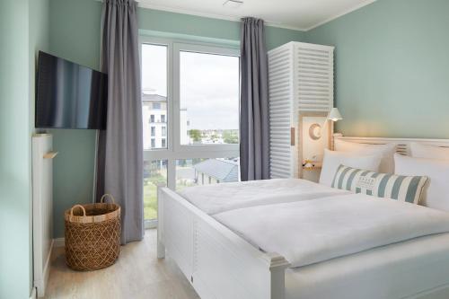 a bedroom with a white bed and a large window at Beach Apartments Büsum in Büsum